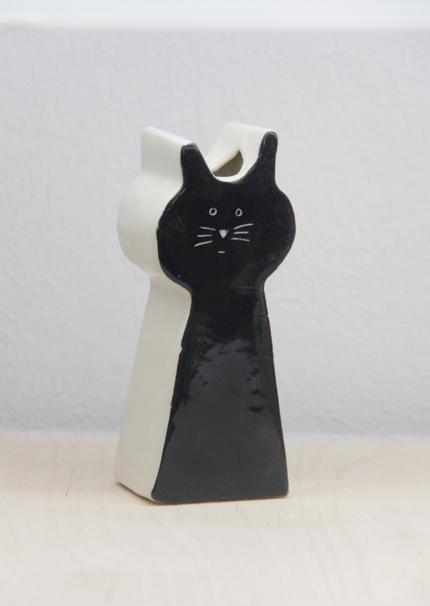 Ceramic cat-shaped vase with black and white design on a light background