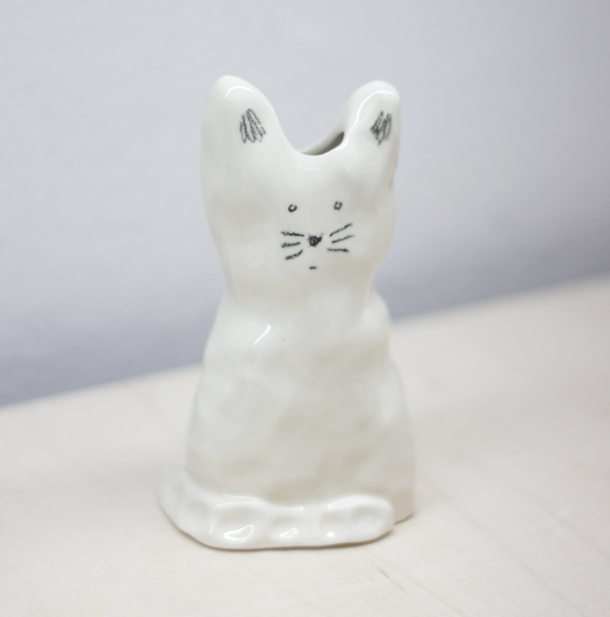 White ceramic cat-shaped vase on a light gray background